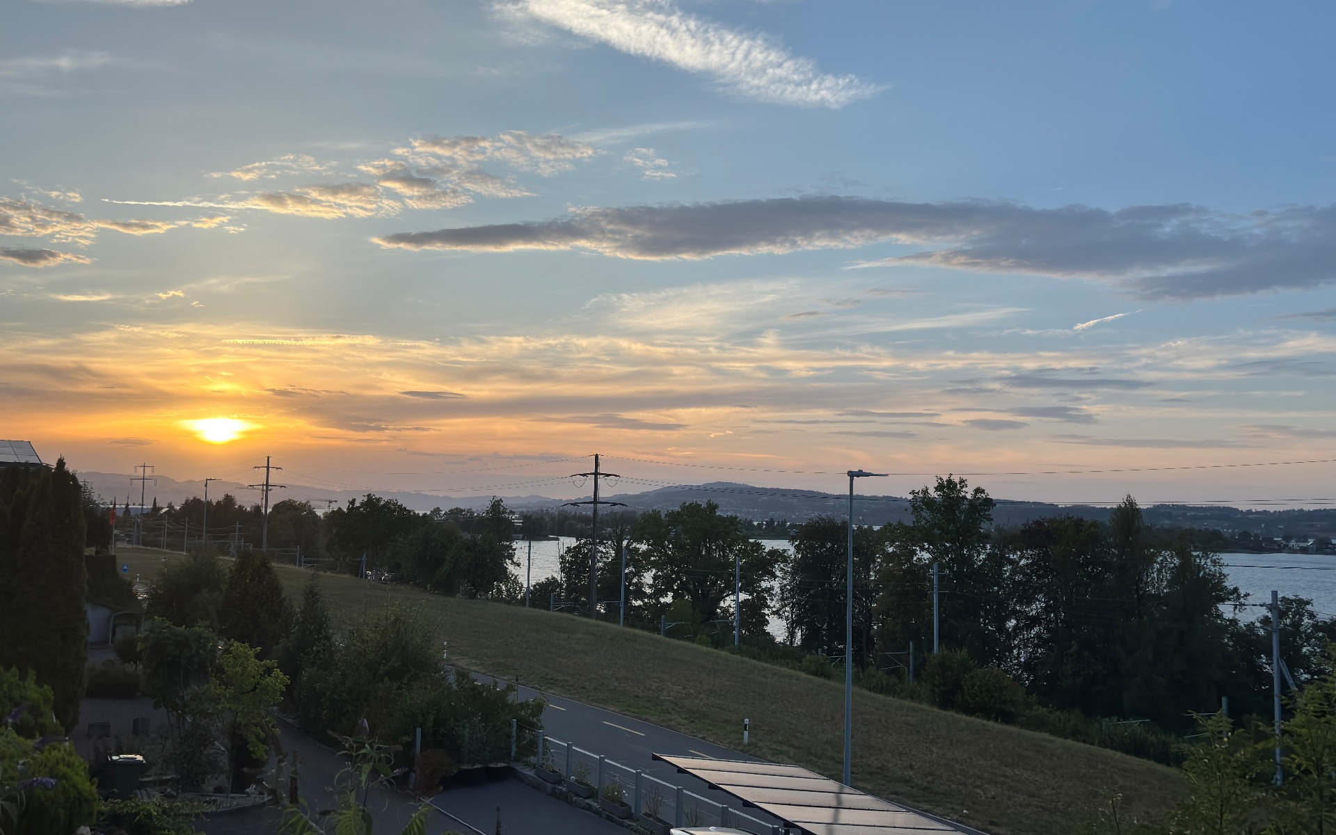 Goldene Abendstimmung über dem Zürichsee mit Wolkenhimmel, Uferlinie und bewaldeten Hügeln